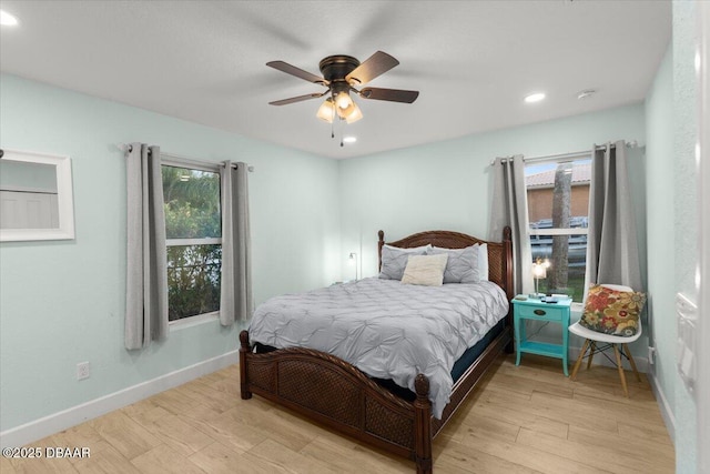 bedroom with ceiling fan, multiple windows, and light wood-type flooring