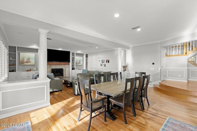 dining room with ornate columns, ornamental molding, built in features, and light hardwood / wood-style flooring