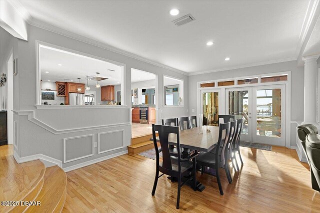 dining room featuring ornamental molding, light hardwood / wood-style floors, french doors, and decorative columns