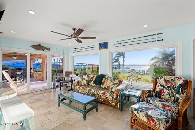 living room featuring ceiling fan and a water view