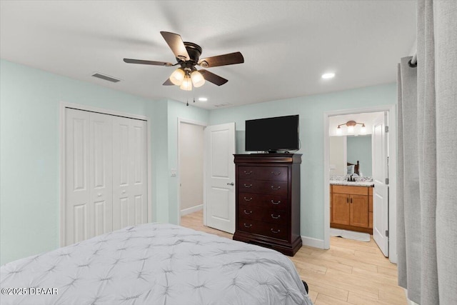 bedroom featuring ensuite bath, light hardwood / wood-style floors, sink, a closet, and ceiling fan