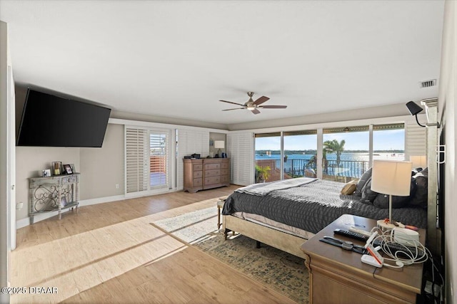 bedroom featuring ceiling fan, multiple windows, hardwood / wood-style flooring, and access to outside