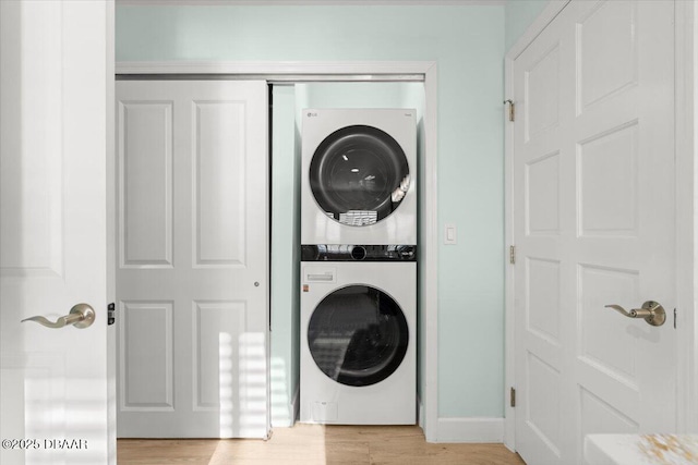 laundry area with stacked washer and clothes dryer and light hardwood / wood-style flooring