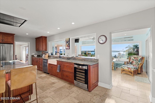 kitchen featuring beverage cooler, black electric stovetop, sink, stainless steel fridge, and a breakfast bar