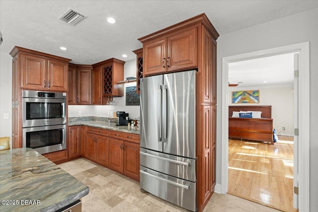 kitchen featuring a textured ceiling, appliances with stainless steel finishes, and light stone countertops