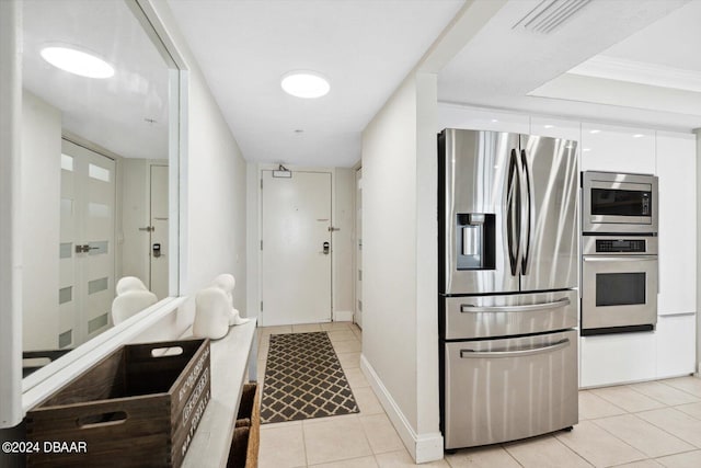 interior space with crown molding, white cabinetry, stainless steel appliances, and light tile patterned floors