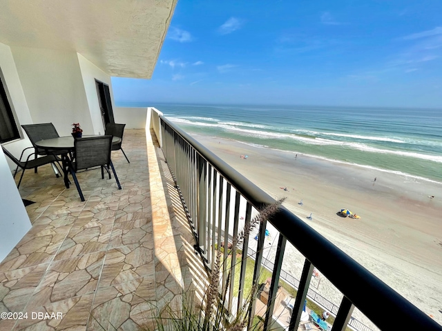 balcony featuring a view of the beach and a water view