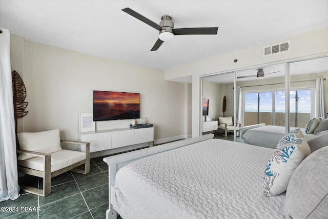 bedroom featuring dark tile patterned floors, a closet, and ceiling fan