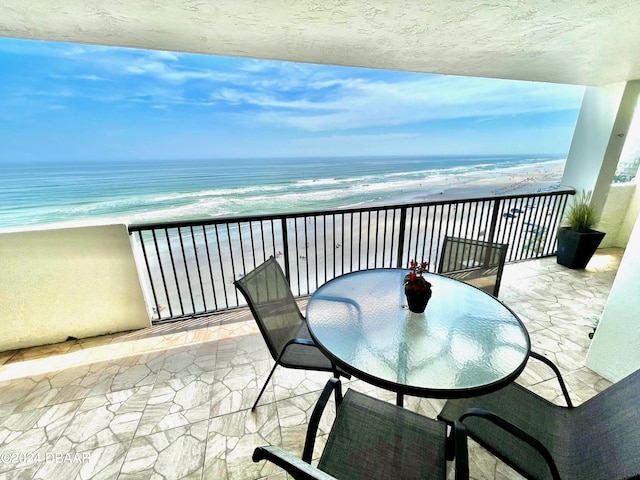 balcony with a water view and a view of the beach