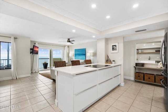 kitchen with a kitchen breakfast bar, ceiling fan, light tile patterned floors, black electric cooktop, and white cabinetry