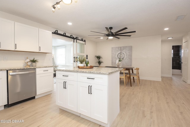 kitchen featuring stainless steel dishwasher, a barn door, and white cabinets