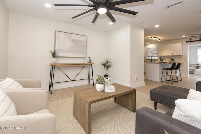 living room featuring sink, ceiling fan, and light hardwood / wood-style flooring