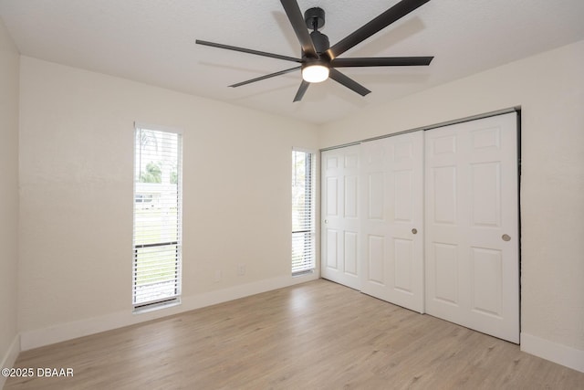 unfurnished bedroom featuring multiple windows, a closet, ceiling fan, and light hardwood / wood-style floors