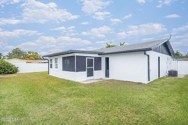 back of house with cooling unit, a sunroom, and a lawn