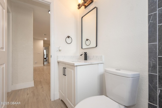 bathroom with wood-type flooring, toilet, and vanity