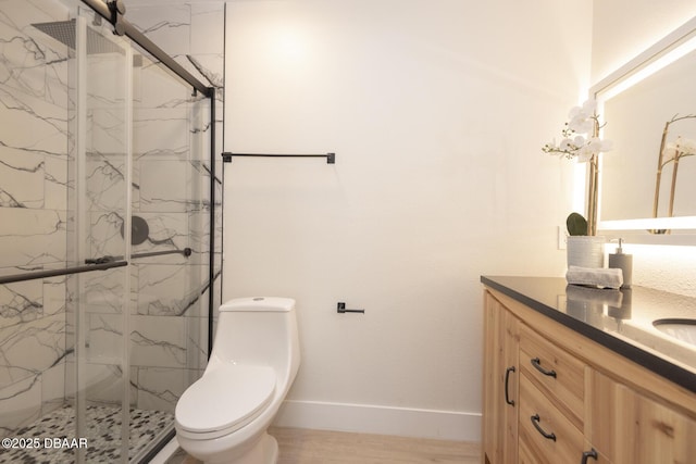 bathroom featuring vanity, a shower with shower door, and toilet