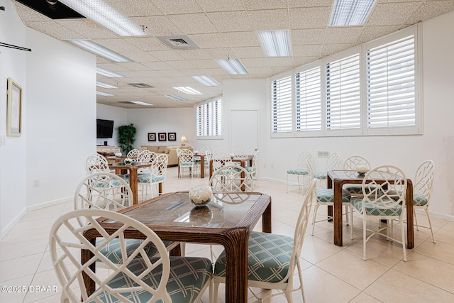 tiled dining space featuring a drop ceiling