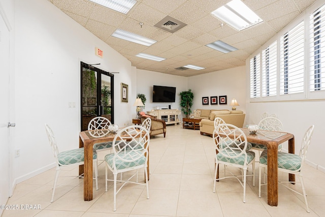 tiled dining space featuring a drop ceiling