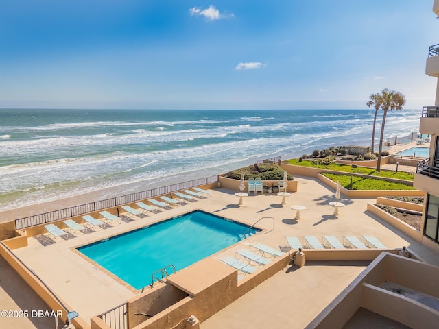 view of swimming pool with a patio, a beach view, and a water view