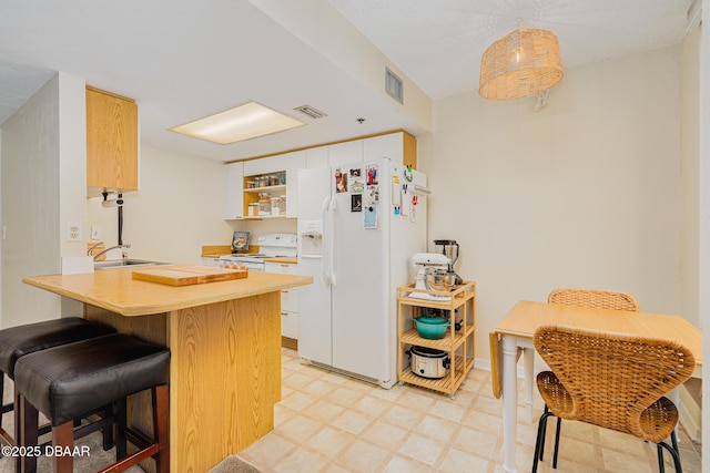 kitchen with white appliances, kitchen peninsula, a kitchen bar, white cabinets, and sink