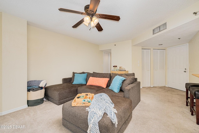 living room featuring light carpet, ceiling fan, and a textured ceiling