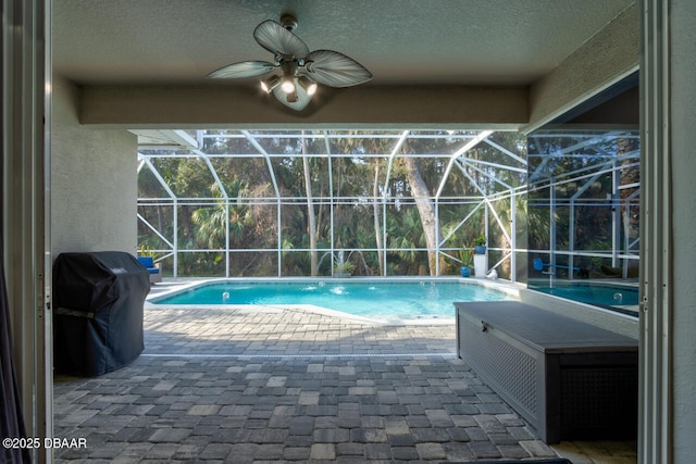 view of swimming pool featuring grilling area, ceiling fan, glass enclosure, and a patio