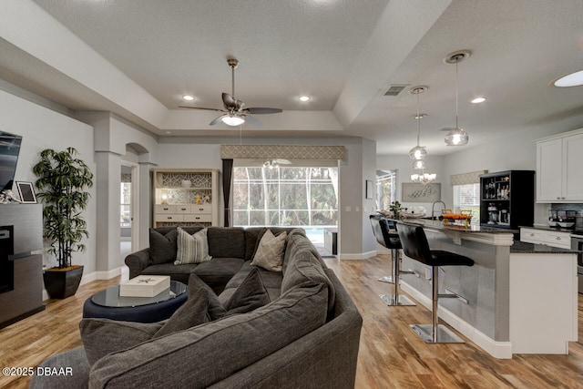 living room featuring a tray ceiling, plenty of natural light, and light hardwood / wood-style floors