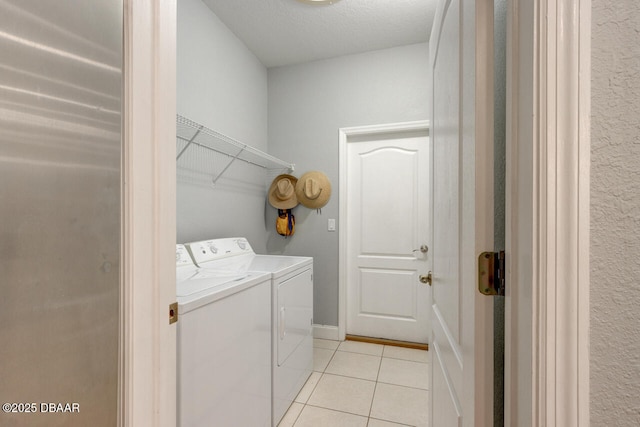 clothes washing area with light tile patterned floors, washer and clothes dryer, and a textured ceiling