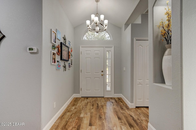 entryway featuring hardwood / wood-style flooring, lofted ceiling, plenty of natural light, and a notable chandelier