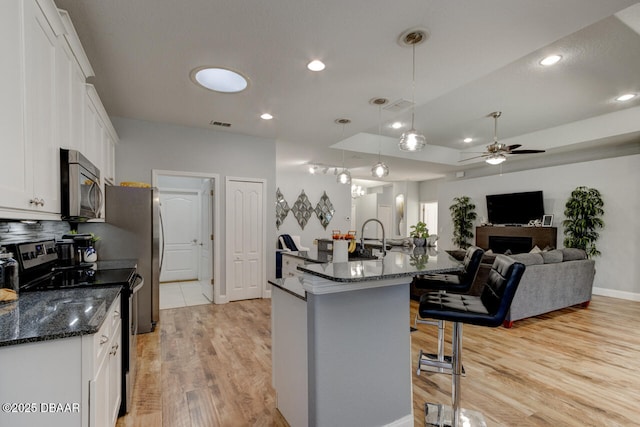 kitchen with white cabinetry, a breakfast bar, electric range oven, and pendant lighting