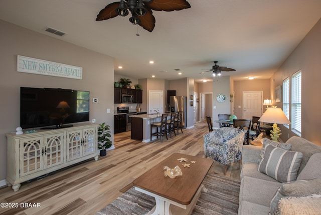 living room with light wood-style flooring, visible vents, a ceiling fan, and recessed lighting