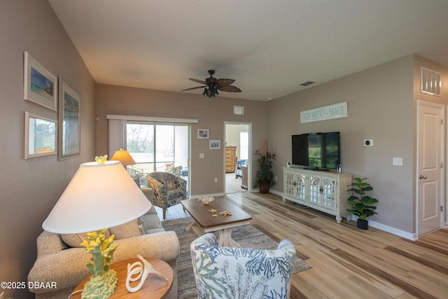 living room featuring light wood-style flooring, visible vents, ceiling fan, and baseboards