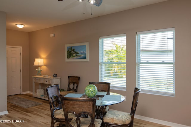 dining space featuring baseboards, ceiling fan, and light wood finished floors