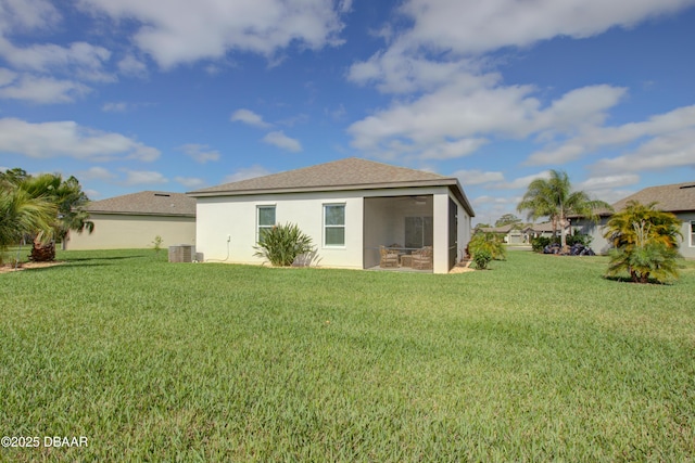 rear view of property featuring a yard, a sunroom, central AC, and stucco siding