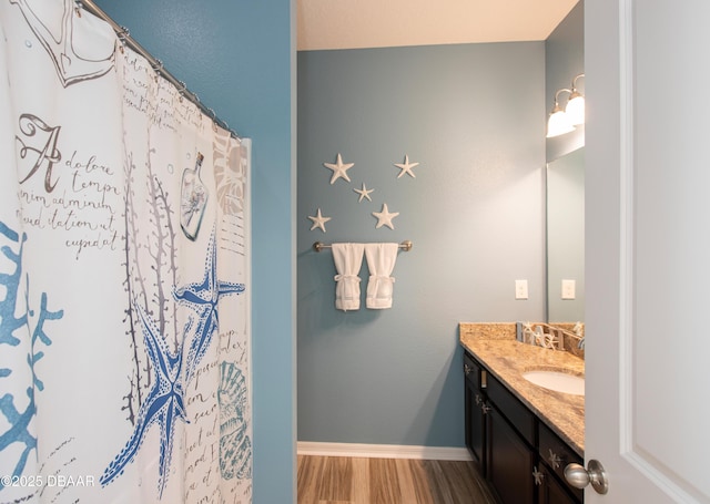 bathroom with a shower with shower curtain, vanity, baseboards, and wood finished floors