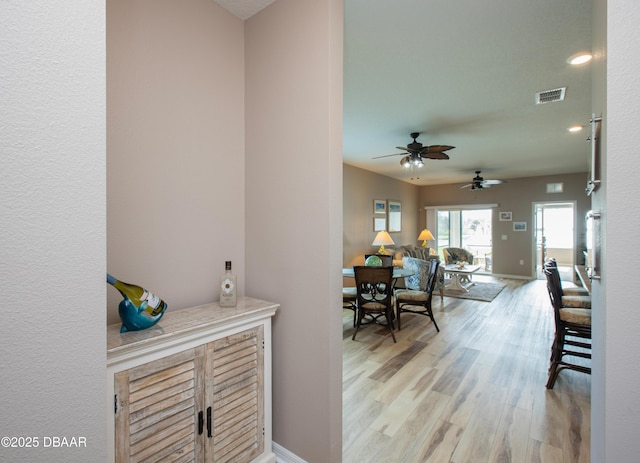 bar with baseboards, visible vents, and light wood finished floors