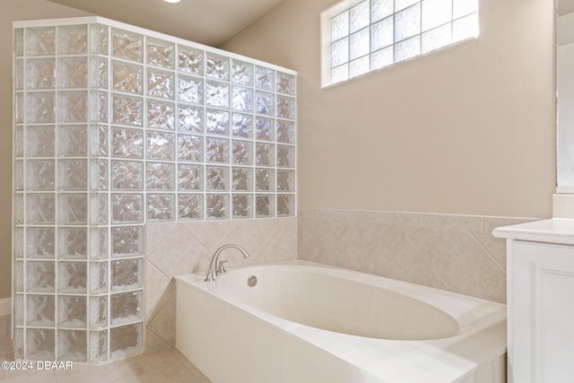 bathroom featuring vanity, tile patterned floors, tile walls, and a tub