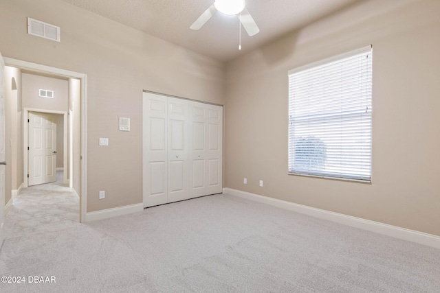 unfurnished bedroom with a closet, ceiling fan, and light colored carpet