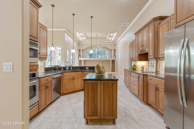 kitchen with sink, stainless steel appliances, dark stone countertops, pendant lighting, and a kitchen island