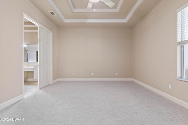 carpeted empty room featuring a raised ceiling, crown molding, and ceiling fan