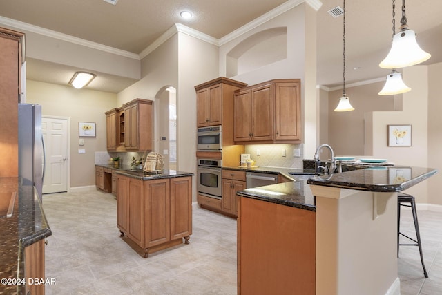 kitchen featuring kitchen peninsula, stainless steel appliances, sink, dark stone countertops, and hanging light fixtures