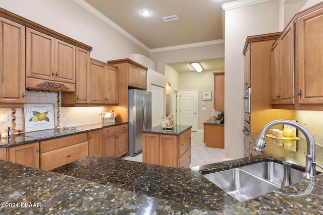 kitchen featuring appliances with stainless steel finishes, backsplash, dark stone counters, crown molding, and sink