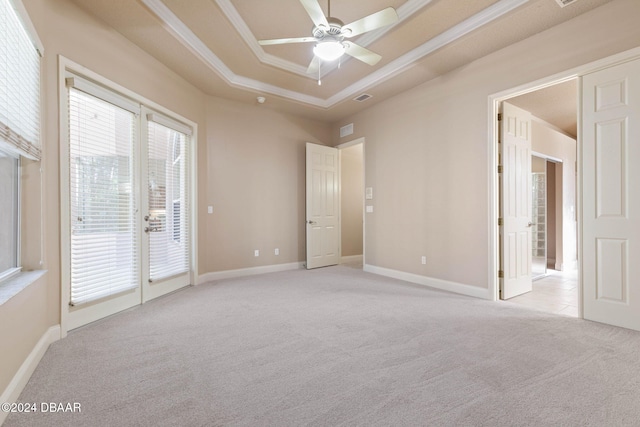 carpeted empty room featuring a raised ceiling, ceiling fan, french doors, and ornamental molding