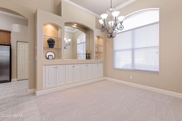 carpeted spare room featuring built in shelves, ornamental molding, and an inviting chandelier