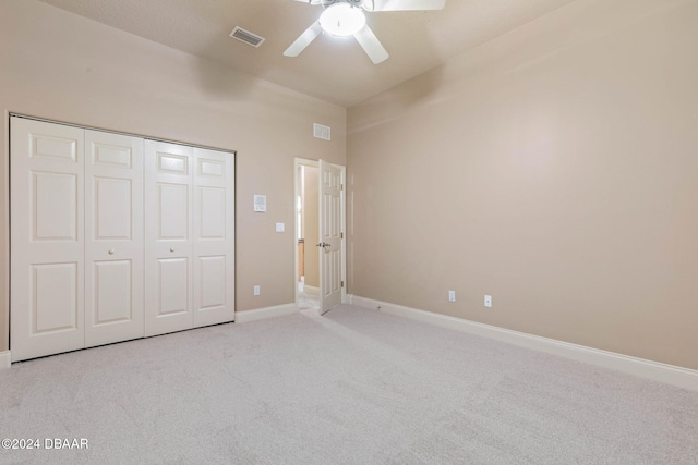 unfurnished bedroom featuring a closet, light colored carpet, and ceiling fan