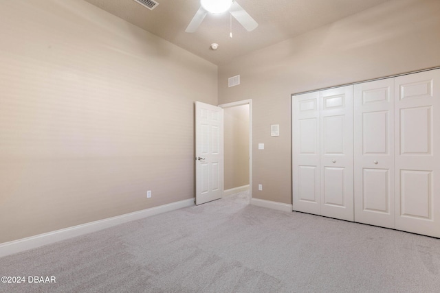 unfurnished bedroom with ceiling fan, light carpet, and a closet