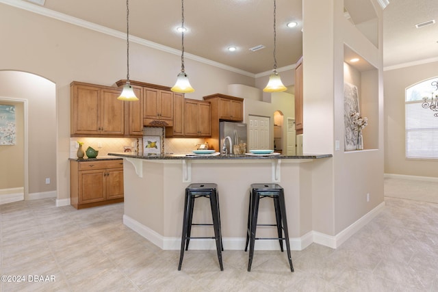 kitchen featuring kitchen peninsula, backsplash, stainless steel refrigerator, and dark stone countertops