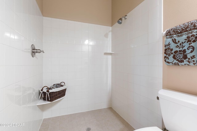 bathroom with tile patterned flooring, a tile shower, and toilet