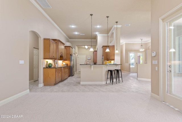 kitchen with pendant lighting, a kitchen breakfast bar, light colored carpet, and stainless steel refrigerator