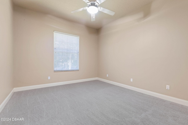 carpeted spare room with ceiling fan and a textured ceiling